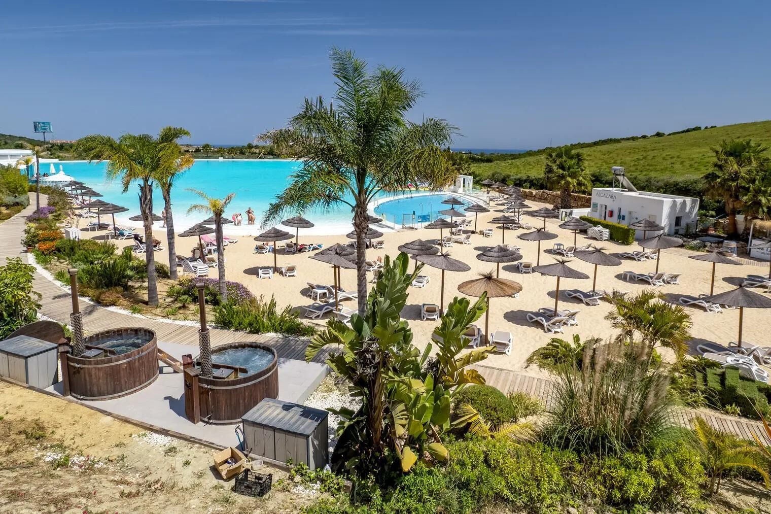 Un resort con una piscina grande, tumbonas y un área de spa.