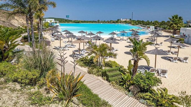 A resort with a large pool, sun loungers, and palm trees. - Luxury 2-bedroom sea View Apartment in Casares (Casares)