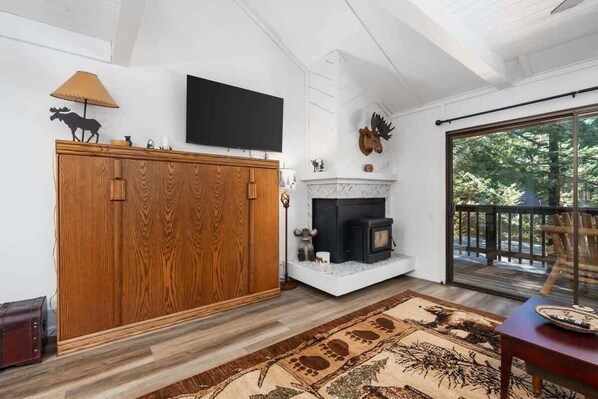 A living room with a fireplace, wooden cabinet, and a television on the wall.