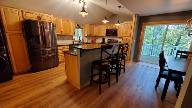 Una cocina con armarios de madera, un refrigerador de acero inoxidable, un microondas y una isla grande con taburetes de bar.