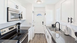 A compact kitchen with a microwave, oven, and sink. - Dazzle-In Old Town-Walk to Entertainment District (Scottsdale)