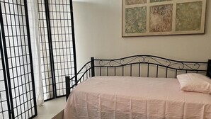 Una camera da letto con un letto, una finestra vista e un paravento decorativo.
