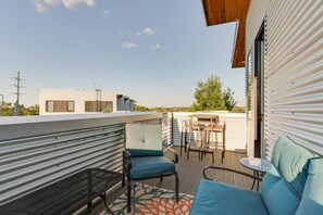 A rooftop terrace with a seating area, a table, and a view of the surrounding buildings.