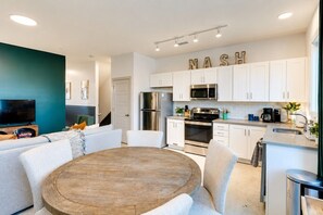 A modern kitchen with white cabinets, stainless steel appliances, and a 'NASH' sign on the wall. - King Suite and Spacious Balcony Near Broadway (Nashville)