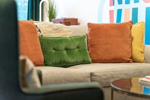 A sofa with three cushions in different colors and a small table with a book.