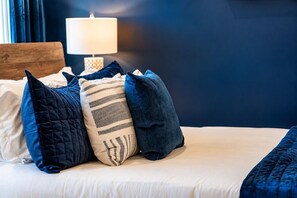 A bed with multiple pillows and a bedside lamp. - King Suite and Spacious Balcony Near Broadway (Nashville)