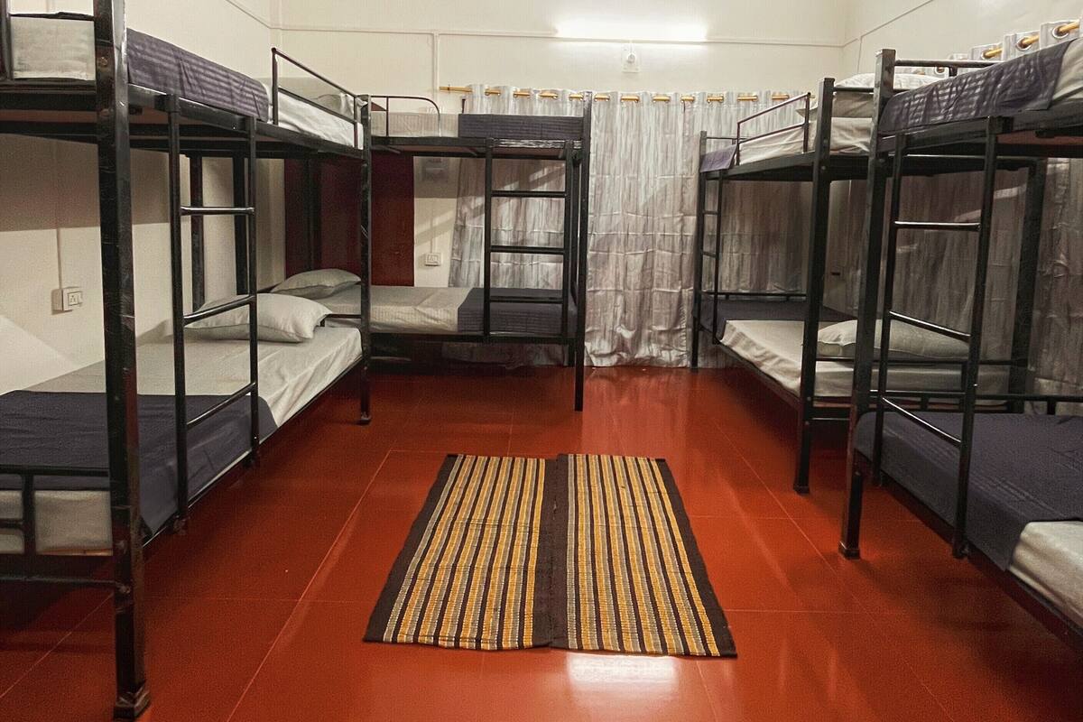 A dormitory room with bunk beds, a ceiling fan, and a striped rug.