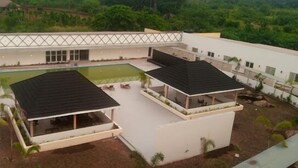 A modern building with a pool, covered outdoor seating, and a landscaped garden. - BON Hotel  (Ado Ekiti)