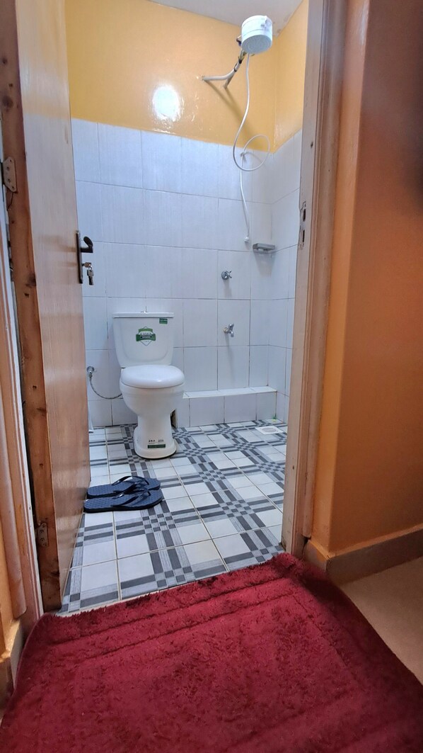 A bathroom with a toilet, a shower, and a tiled floor.
