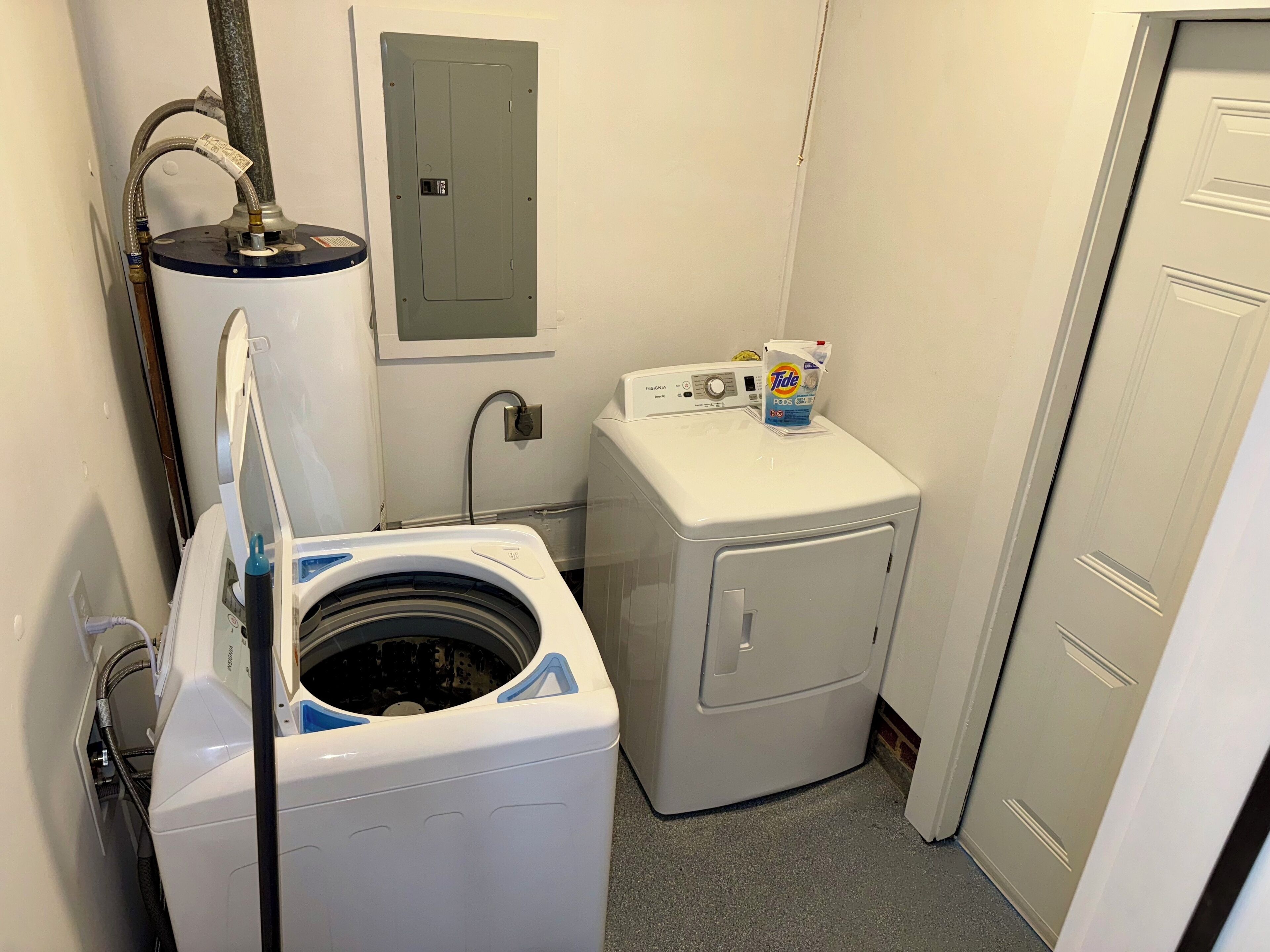 A laundry room with a front-loading washer and dryer, a water heater, and a utility meter.
