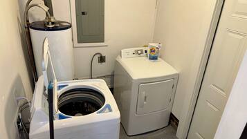 A laundry room with a front-loading washer and dryer, a water heater, and a utility meter.