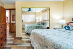 A bedroom with two beds, a wooden dresser, a ceiling fan, and a large mirror. - Kihei Kai Nani #6-349 Remodeled End Unit, Across Kamaole Beach II, Ocean View (Kihei)