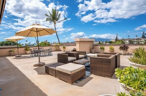 A rooftop patio with wicker furniture, a table, chairs, and potted plants. - Kihei Kai Nani #6-349 Remodeled End Unit, Across Kamaole Beach II, Ocean View (Kihei)
