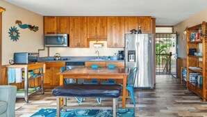 Una cocina con armarios de madera, un refrigerador de acero inoxidable, un microondas y un comedor con banco y sillas.