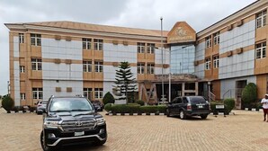 A modern building with a sign reading "Midas Hotel" and a paved driveway with parked cars. - Midas Hotel and Arena  (Ado Ekiti)