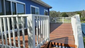 A blue building with a wooden deck and white railings. - Ocean Blue - Linen,  WiFi, Kayo and Pet Friendly (Venus Bay)
