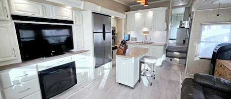 A modern kitchen with white cabinetry, a large refrigerator, a built-in oven, and a central island with bar stools.
