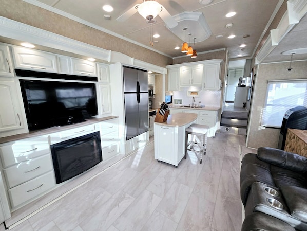 A modern kitchen with white cabinetry, a large refrigerator, a built-in oven, and a central island with bar stools.