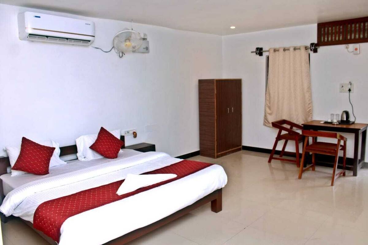 Una habitación de hotel con cama, escritorio, armario y aire acondicionado.