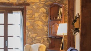 A cozy living room with a stone wall, wooden furniture, and a large window. - Zelaikoa Goikoa - baskeyrentals (Zestoa)