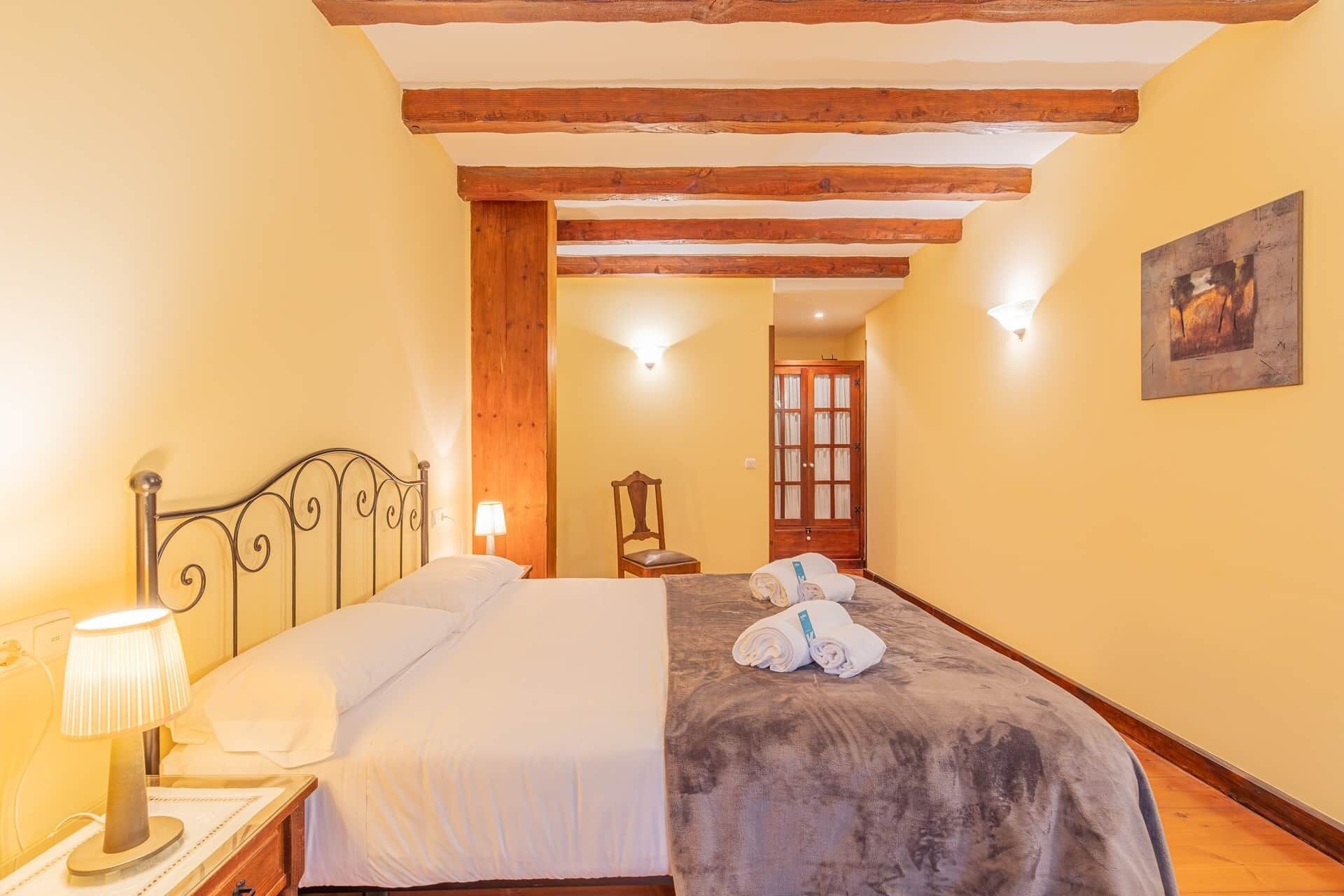 A hotel room with a bed, a nightstand, a lamp, a chair, and a door.