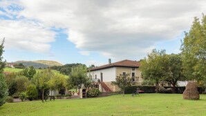 A house with a garden, a picnic table, and a view of hills in the background.