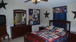 A bedroom with a bed, dresser, mirror, and a ceiling fan.