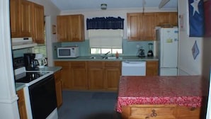 A compact kitchen with wooden cabinets, a microwave, a coffee maker, and a refrigerator.