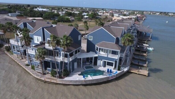 A coastal residential area with multiple two-story houses featuring balconies, a swimming pool, and a view of the sea. - Pelican Point #4 - Great Complex! Great Views! Cool off in the swimming pool! (Port Mansfield)