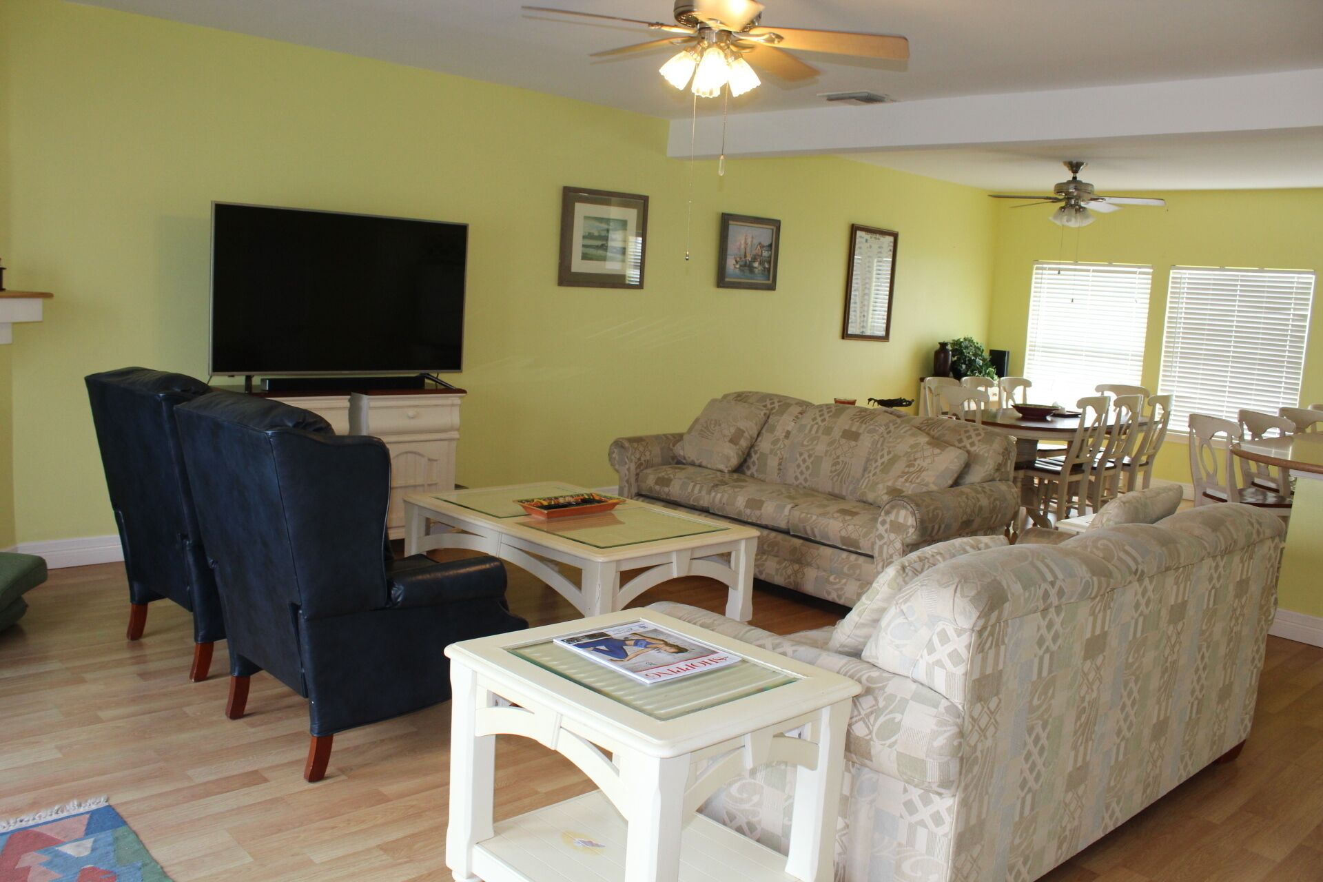 A living room with a sofa, chairs, a coffee table, a TV, and a ceiling fan.