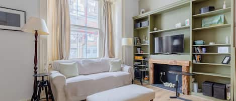 A living room with a sofa, a coffee table, a fireplace, and a bookshelf.