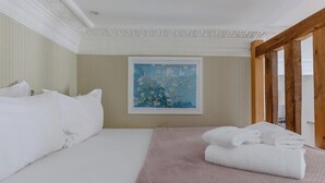 Une chambre d’hôtel avec un lit, des oreillers, un tableau et une structure en poutres apparentes.
