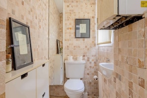 A bathroom with a toilet, sink, tiled walls, and a framed picture on the wall.