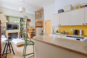 Une cuisine compacte avec un coin repas, un téléviseur intégré et un escalier menant à une mezzanine.