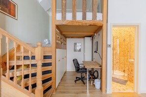 Ein Zimmer mit einer Holztreppe, einem Schreibtisch mit Stuhl und einem Duschbereich.