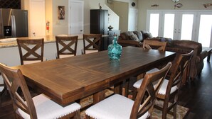 A spacious dining area with a wooden table and chairs, a kitchen in the background, and a living room with a sofa and a ceiling fan. - Pelican Point #6 -Great Complex! Great Views! Cool off in the swimming Pool! (Port Mansfield)