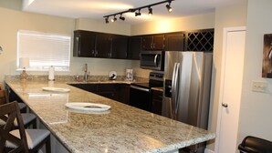 A kitchen with granite countertops, dark cabinets, stainless steel appliances, and a built-in oven. - Pelican Point #6 -Great Complex! Great Views! Cool off in the swimming Pool! (Port Mansfield)