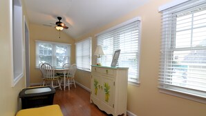 A dining area with a table, chairs, a ceiling fan, and a cabinet with decorative pineapple doors.
