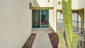 Un étroit sentier mène à une porte-fenêtre coulissante qui donne accès à un bâtiment, avec un cactus au premier plan.