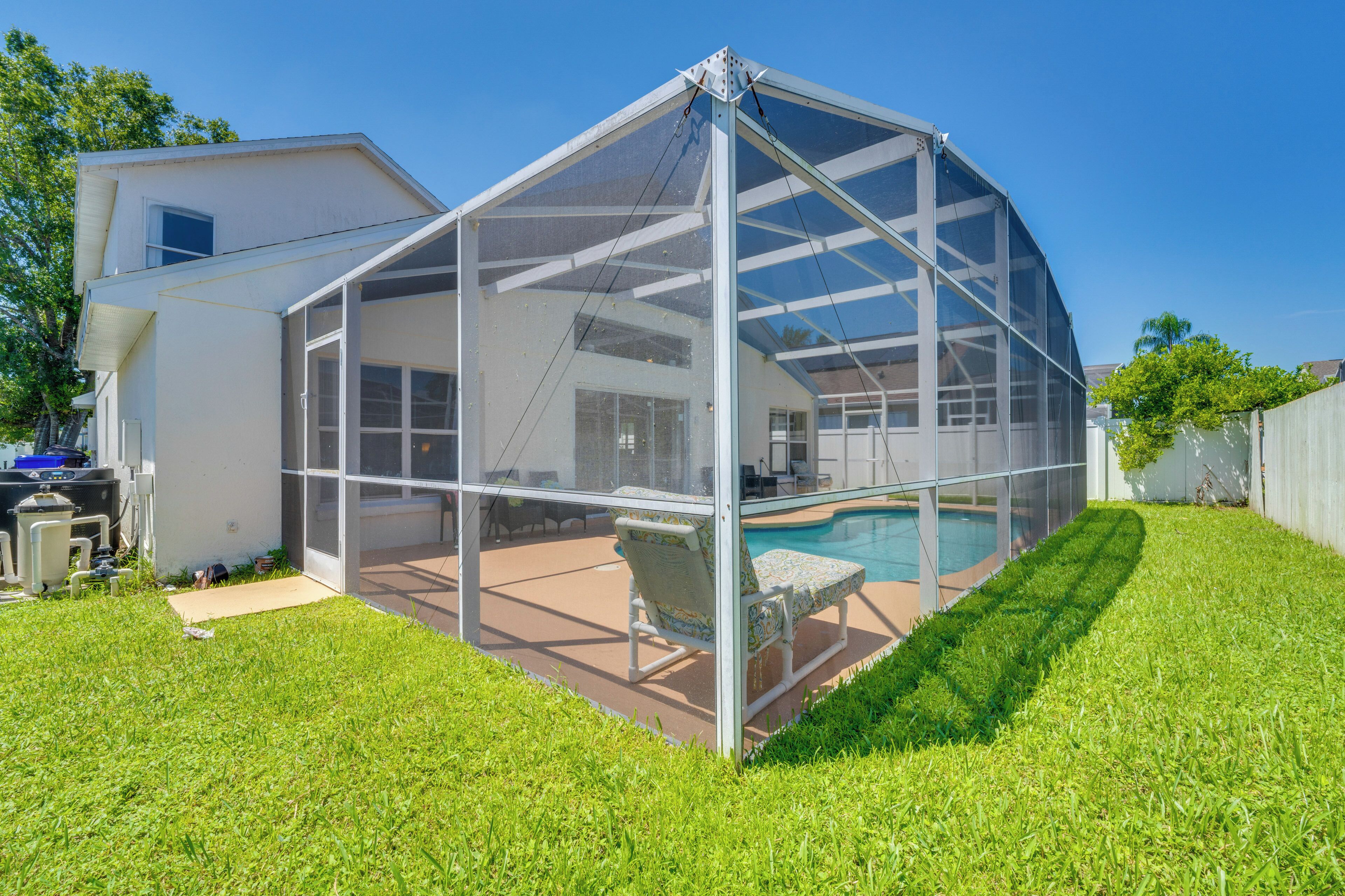 A house with a large enclosed patio area, a pool, and a covered outdoor seating area.