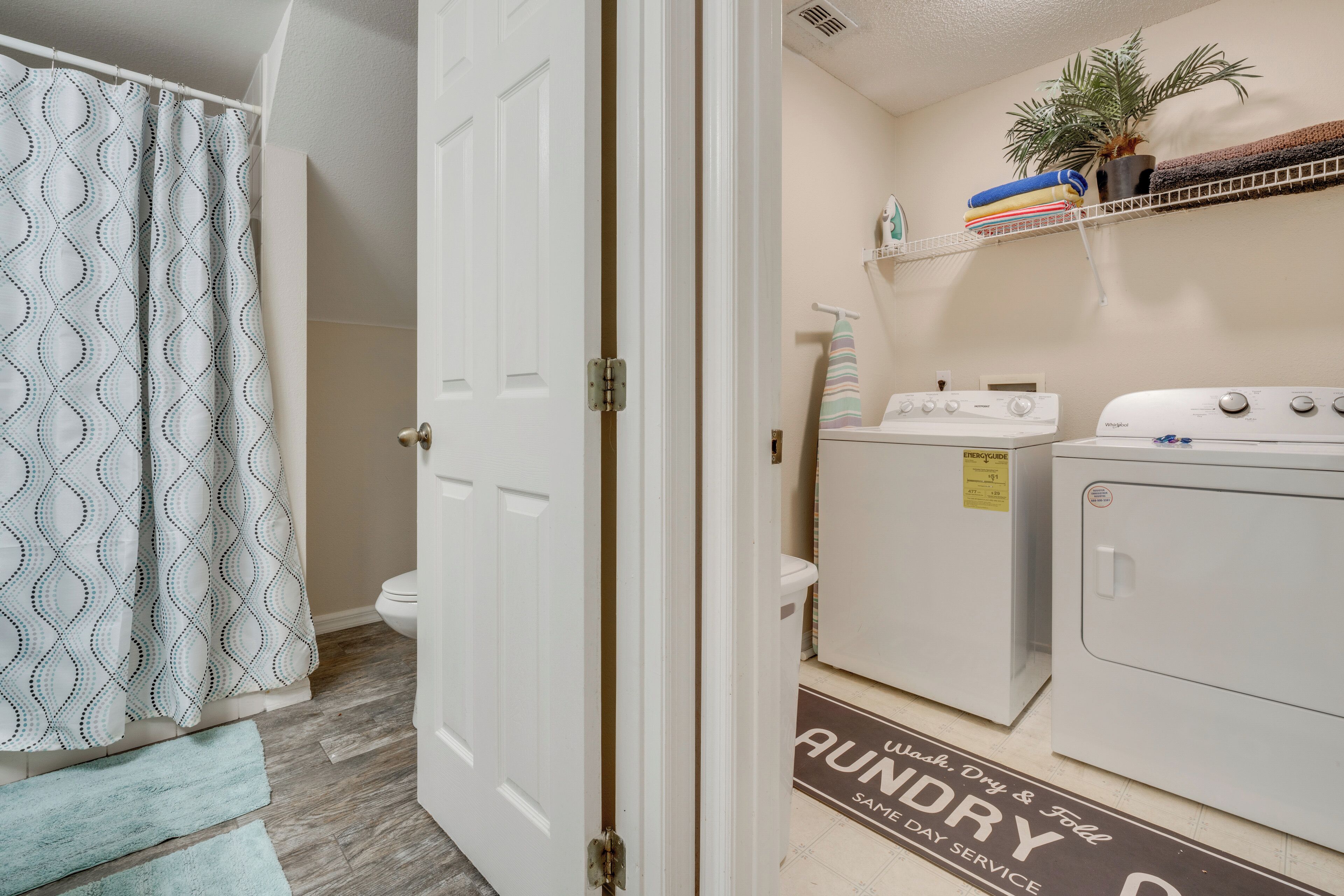 A laundry area with a washing machine, dryer, and a towel rack with folded towels.