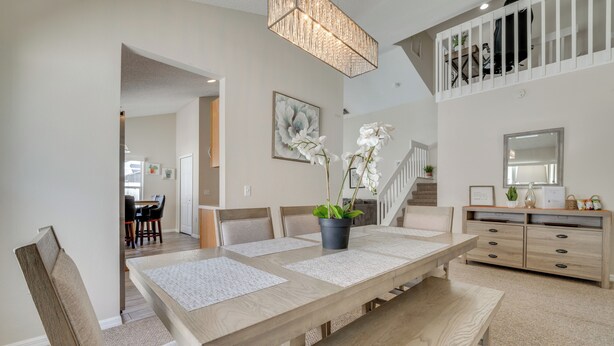 A dining area with a wooden table, chairs, and a bench. There is a staircase leading to an upper level. - 15 Mi to Universal: Home w/ Pool (Kissimmee)
