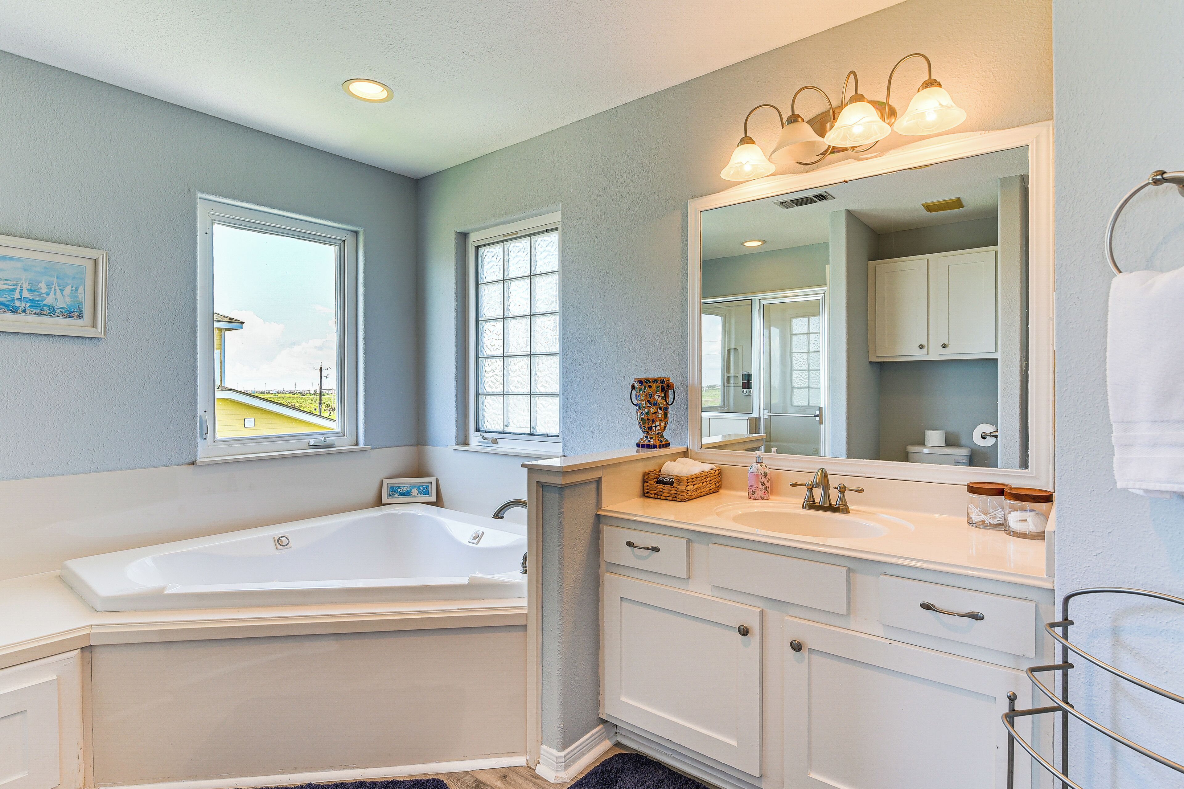 A bathroom with a bathtub, vanity, and a large mirror.