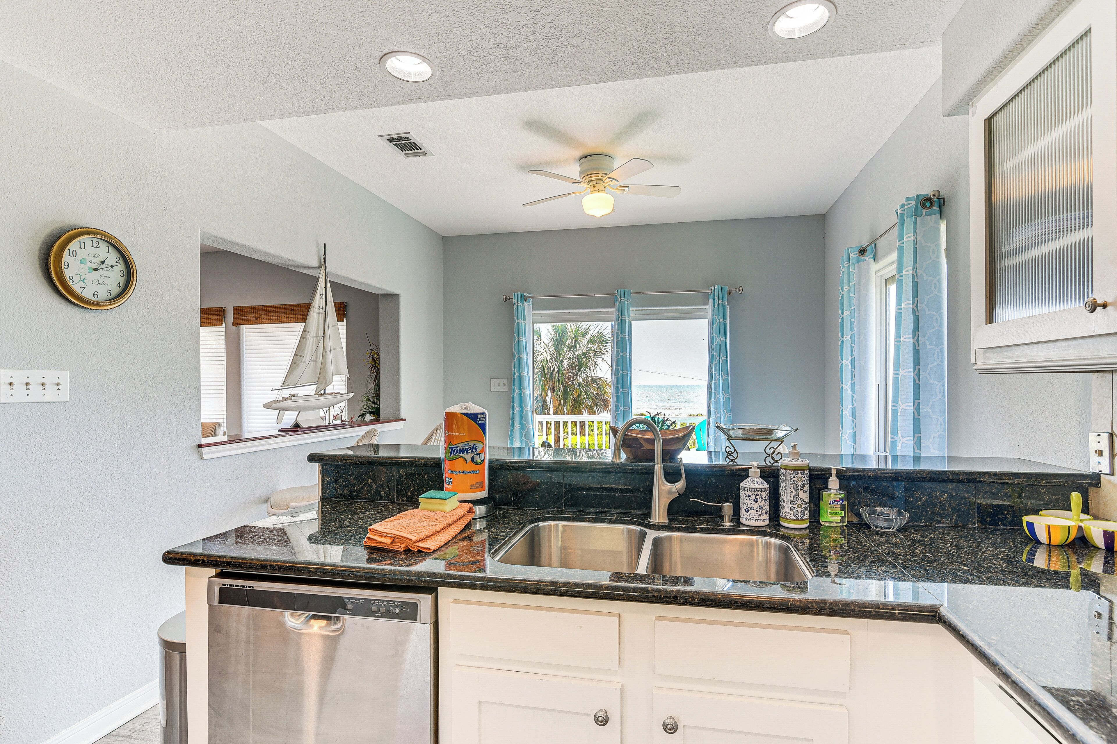 A kitchen with a dishwasher, a sink, and a window with curtains.