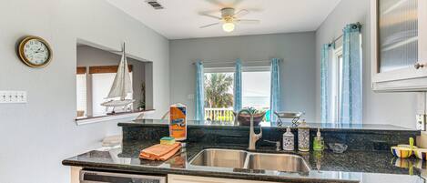 A kitchen with a dishwasher, a sink, and a window with curtains.