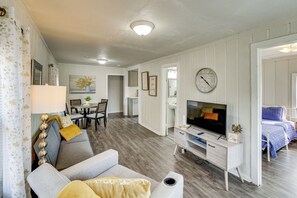 Un salon comprenant un canapé, un téléviseur et un coin repas avec des chaises et une table.