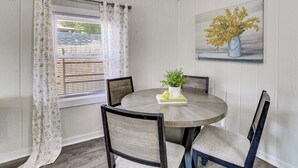 A dining area with a round table, four chairs, a potted plant, and a painting on the wall. - Walk to Dtwn Branson: Pet-friendly Home! (Branson)