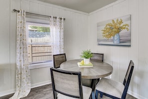 A dining area with a round table, four chairs, a potted plant, and a painting on the wall. - Walk to Dtwn Branson: Pet-friendly Home! (Branson)