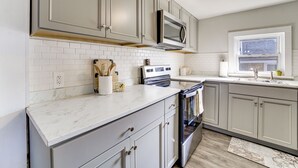 A kitchen with white subway tiles, a stainless steel oven, and a microwave above it. - Walk to Dtwn Branson: Pet-friendly Home! (Branson)
