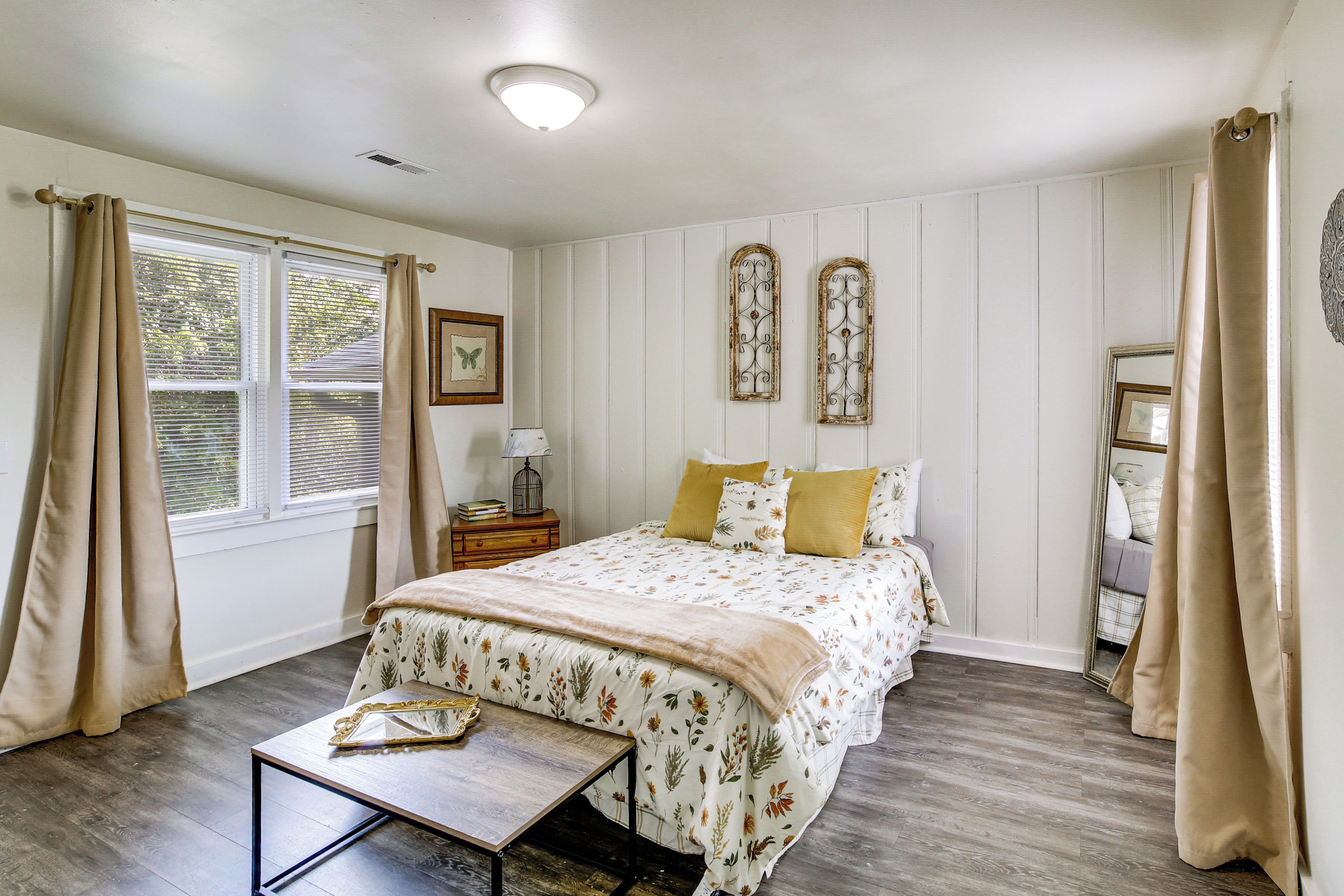 A bedroom with a bed, bedside table, and a window with curtains.